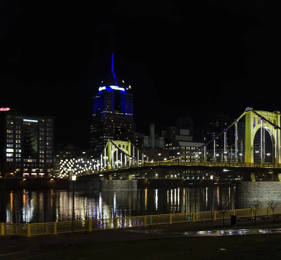 A gold-painted Pittsburgh bridge glowing under night lighting